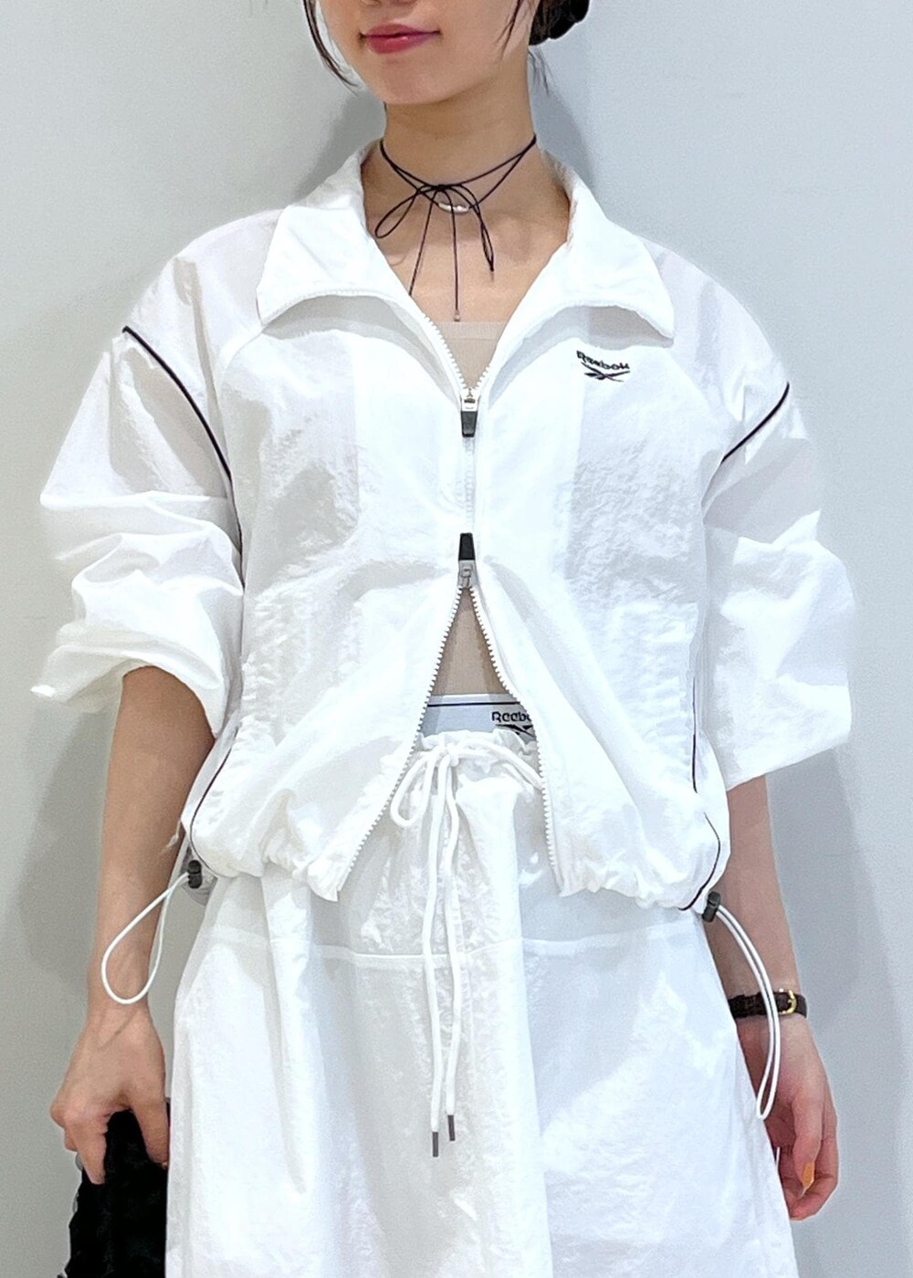 ブラック系のパンプス、ホワイト系のスカート、ベージュ系のキャミソールを着用したレディースの春コーディネートの5枚目の写真