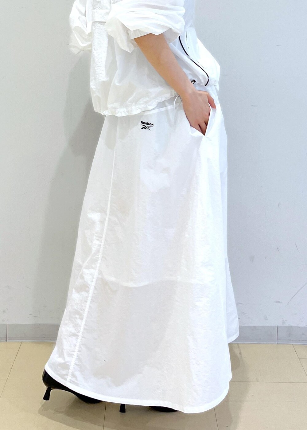 ブラック系のパンプス、ホワイト系のスカート、ベージュ系のキャミソールを着用したレディースの春コーディネートの10枚目の写真