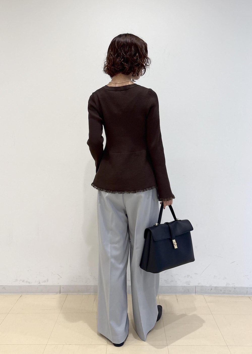 ブラック系のハンドバッグ、ブルー系のその他パンツ、ブラック系のパンプスを着用したレディースの秋コーディネートの4枚目の写真