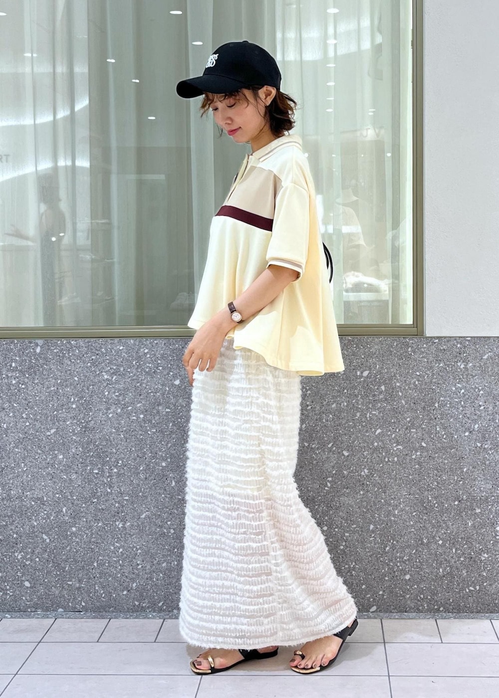 ブラック系のサンダル、ホワイト系のスカート、ベージュ系のポロシャツを着用したレディースの夏コーディネートの2枚目の写真