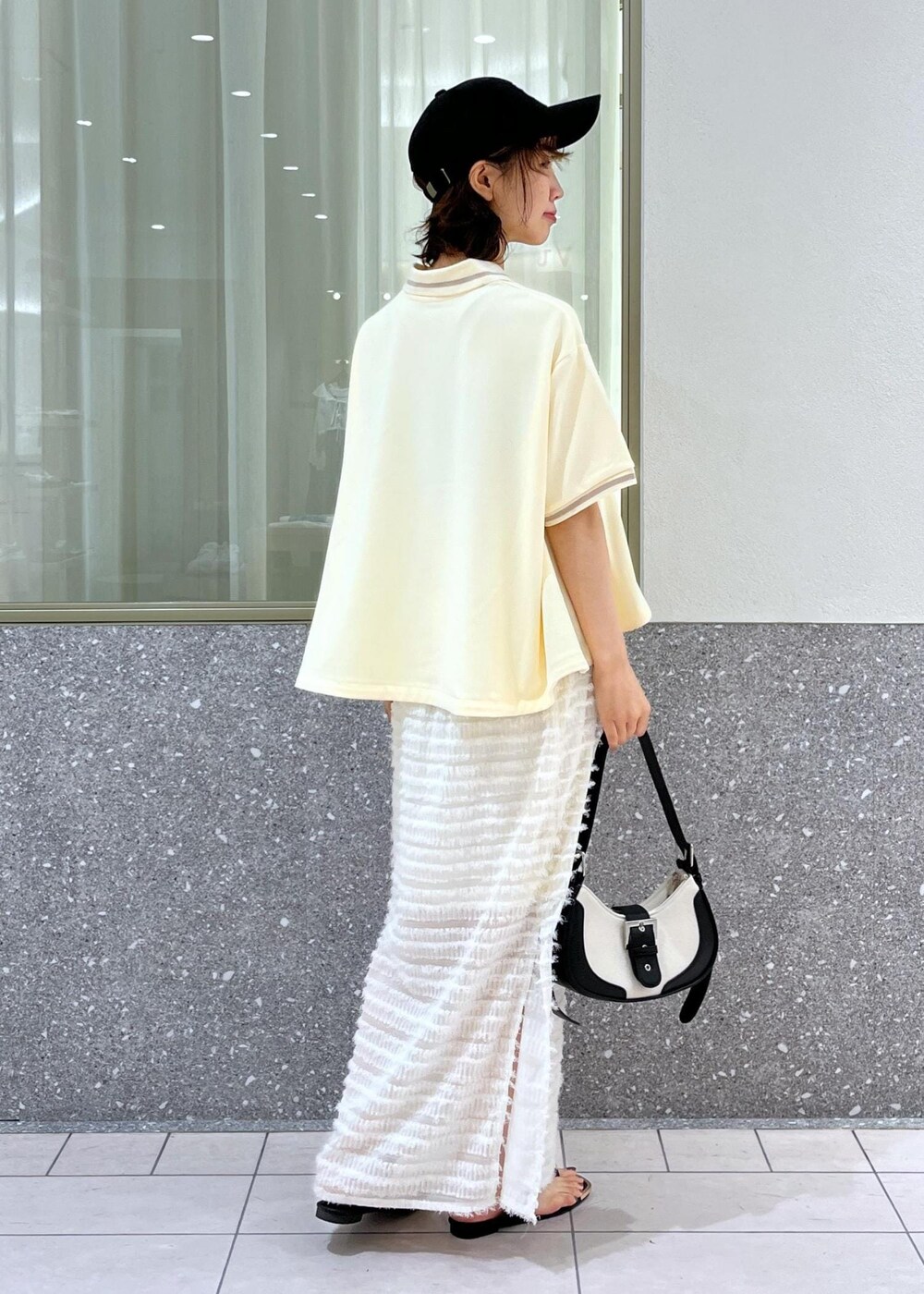 ブラック系のサンダル、ホワイト系のスカート、ベージュ系のポロシャツを着用したレディースの夏コーディネートの4枚目の写真