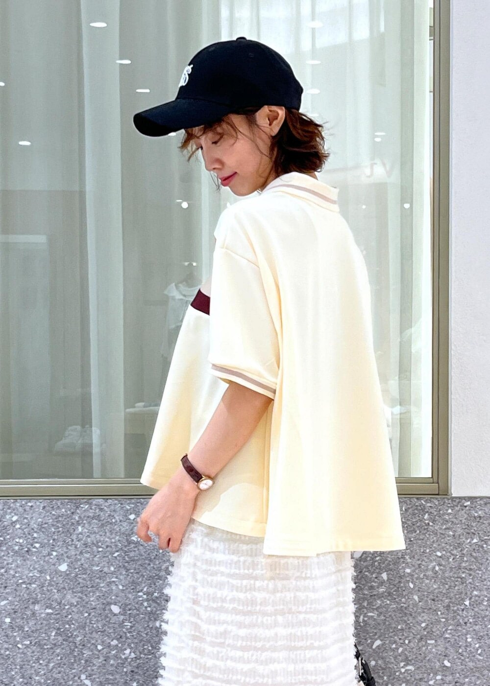 ブラック系のサンダル、ホワイト系のスカート、ベージュ系のポロシャツを着用したレディースの夏コーディネートの10枚目の写真