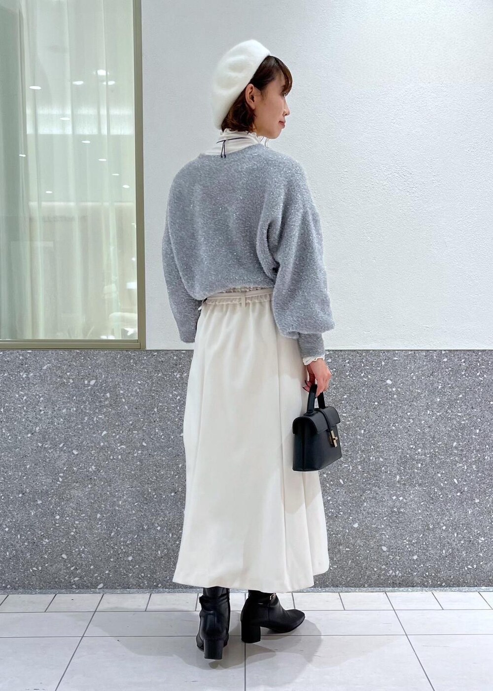 ホワイト系のTシャツ/カットソー、ホワイト系のスカート、グレー系のニット/セーターを着用したレディースの冬コーディネートの3枚目の写真