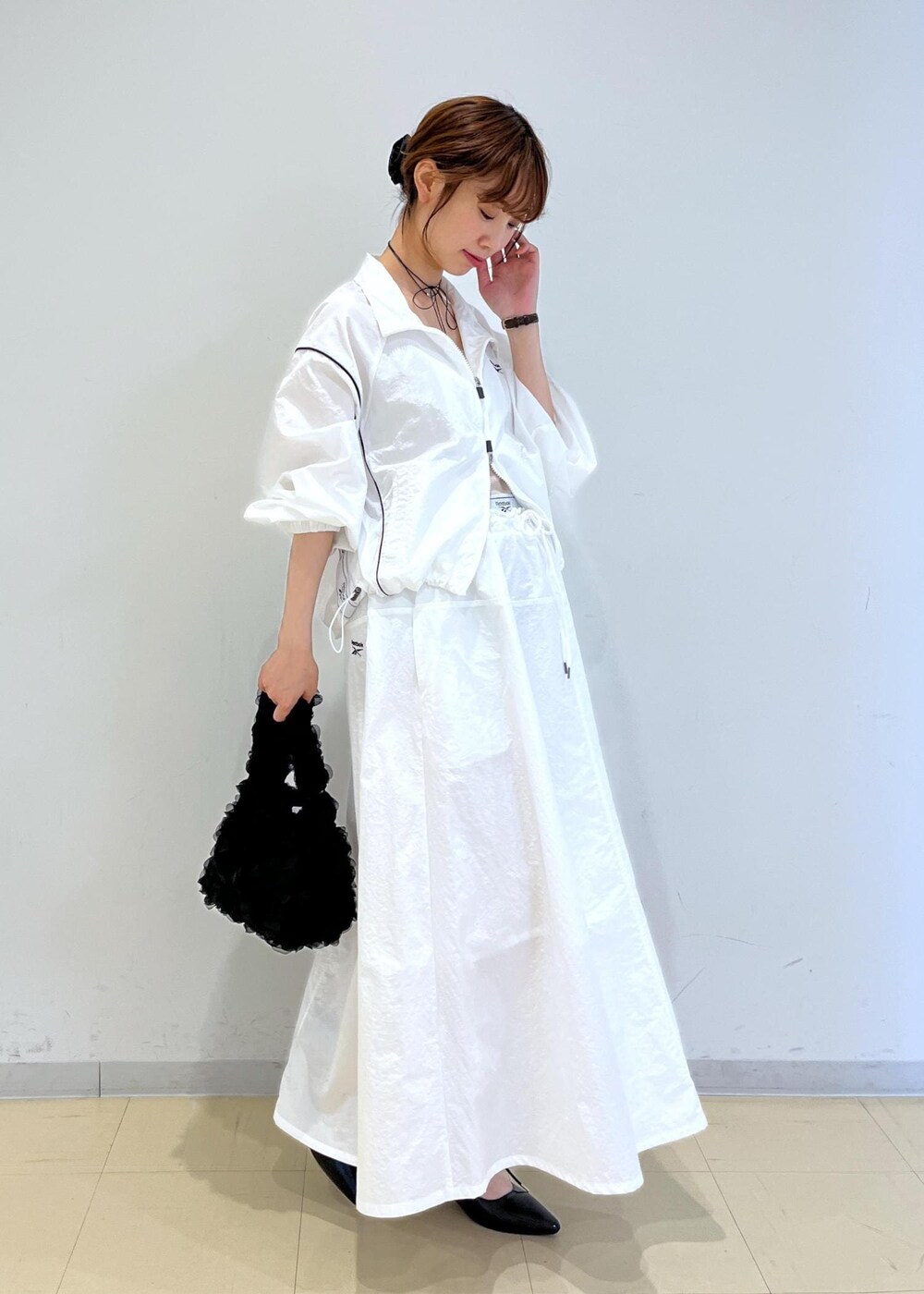 ブラック系のパンプス、ホワイト系のスカート、ベージュ系のキャミソールを着用したレディースの春コーディネートの3枚目の写真