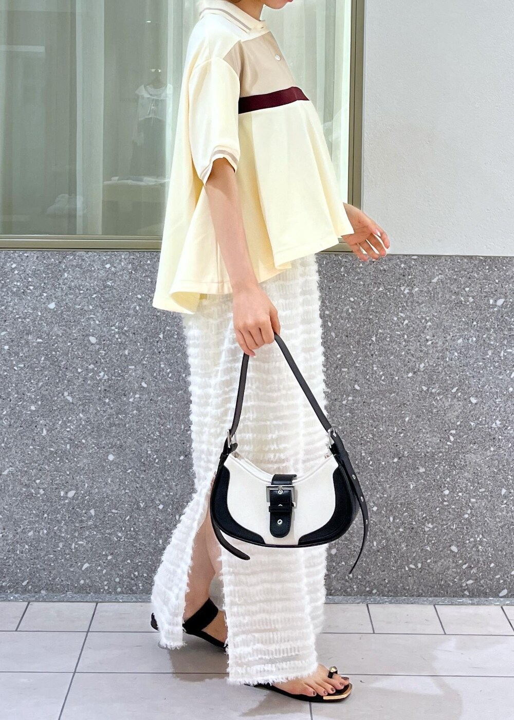 ブラック系のサンダル、ホワイト系のスカート、ベージュ系のポロシャツを着用したレディースの夏コーディネートの6枚目の写真