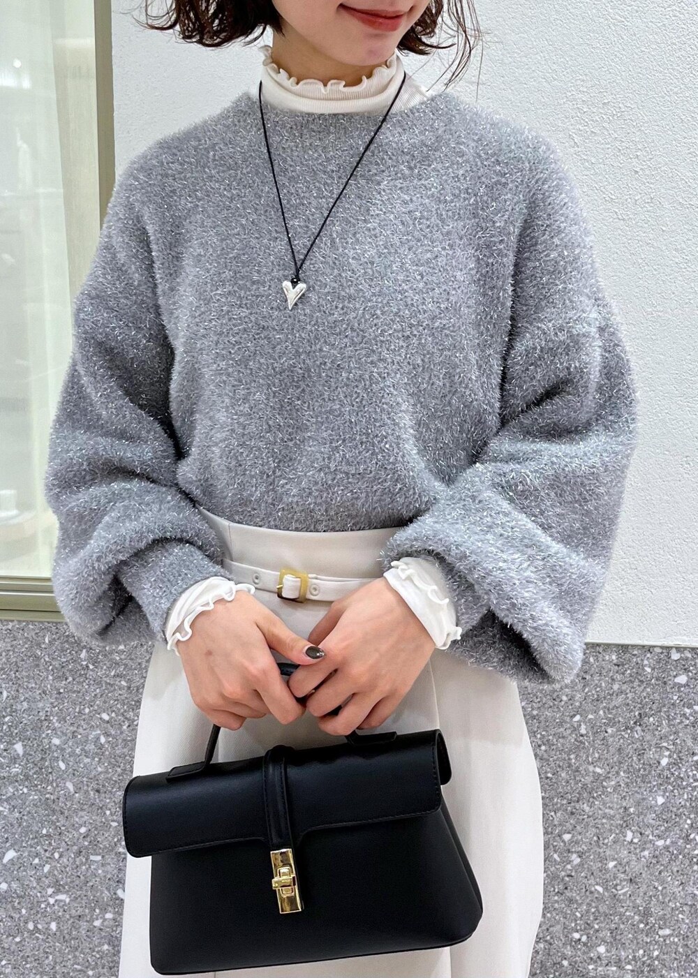 ホワイト系のTシャツ/カットソー、ホワイト系のスカート、グレー系のニット/セーターを着用したレディースの冬コーディネートの4枚目の写真