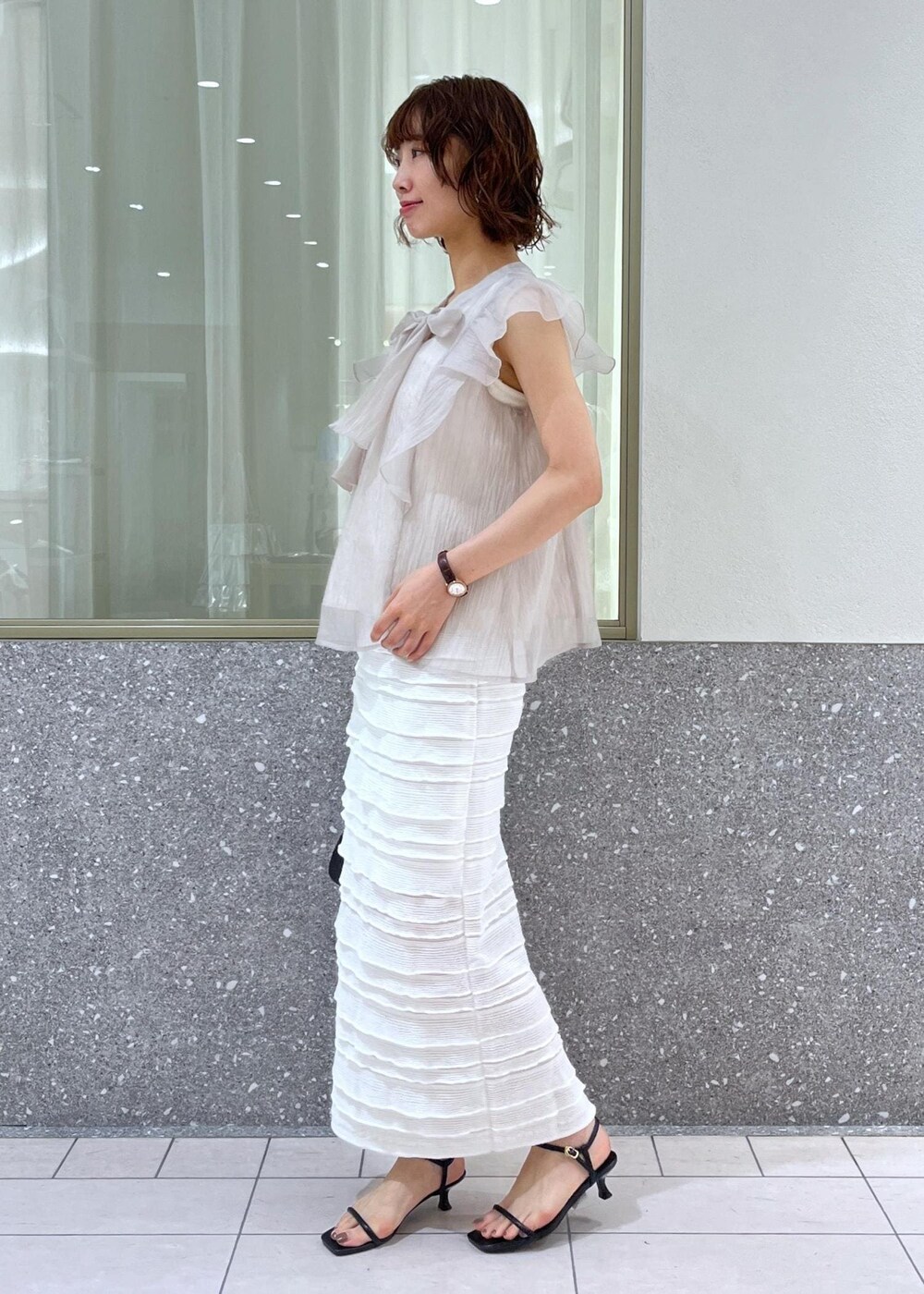 ブラック系のサンダル、ホワイト系のスカート、ホワイト系のキャミソールを着用したレディースの春コーディネートの2枚目の写真