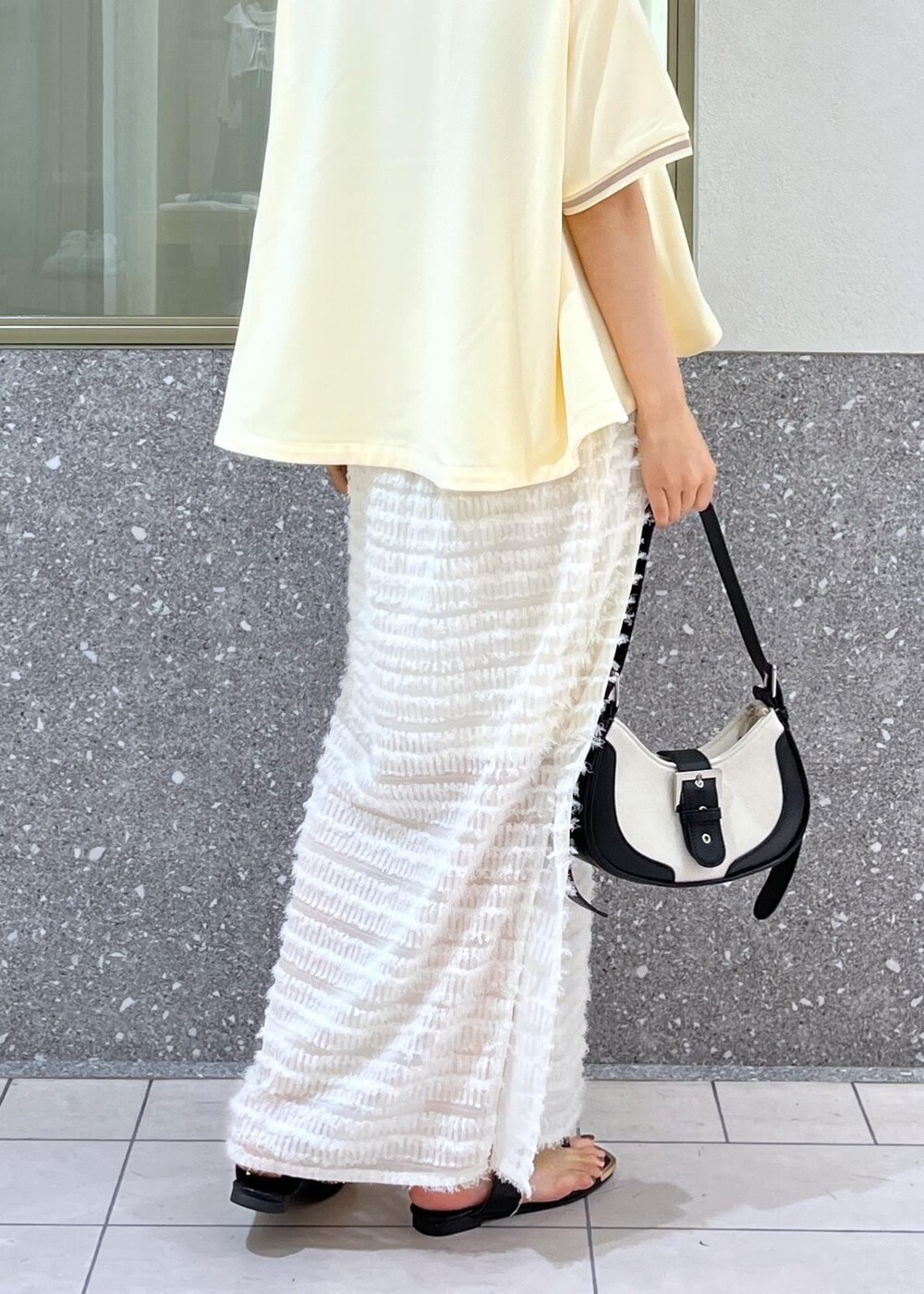 ブラック系のサンダル、ホワイト系のスカート、ベージュ系のポロシャツを着用したレディースの夏コーディネートの5枚目の写真