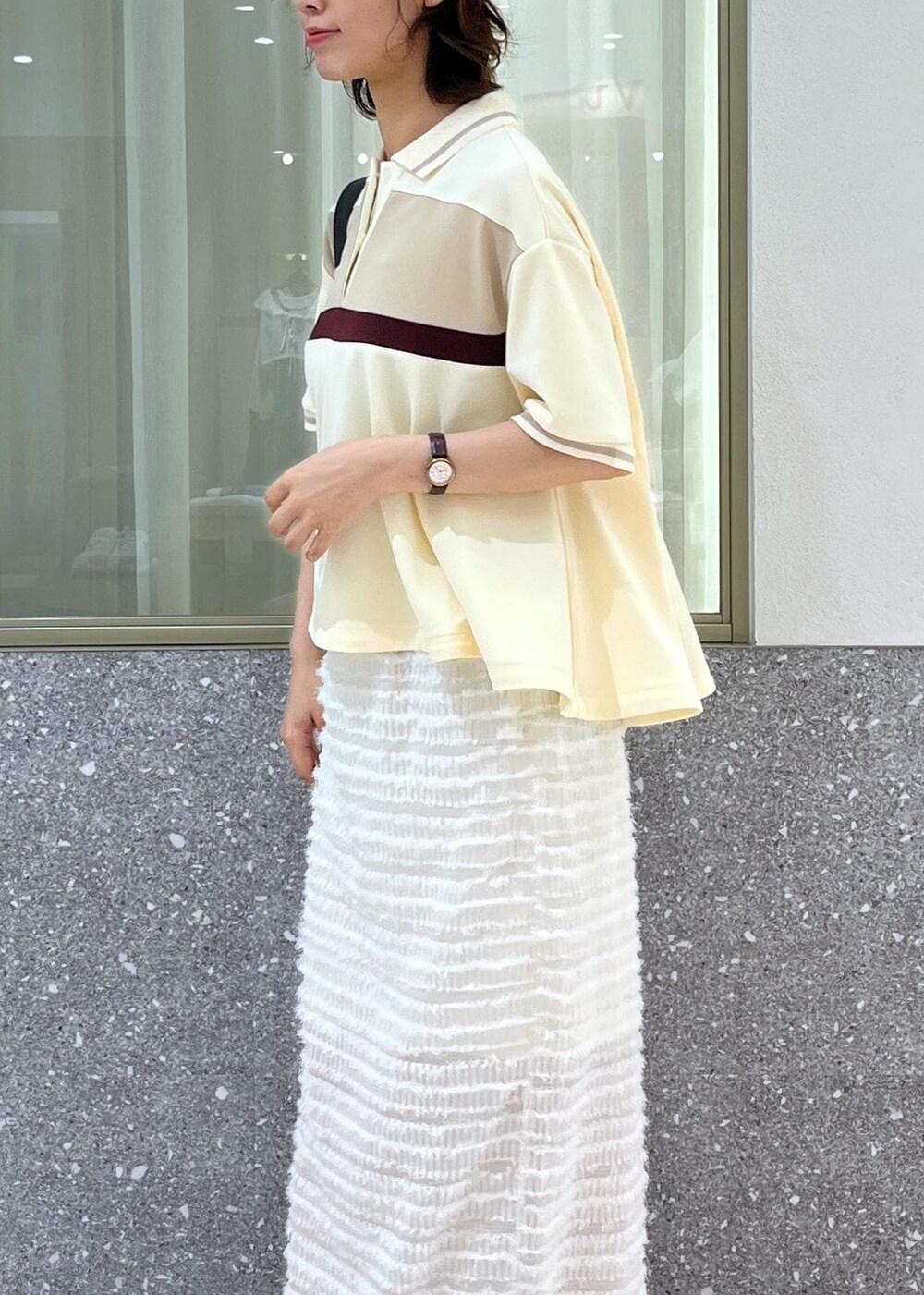 ブラック系のサンダル、ホワイト系のスカート、ベージュ系のポロシャツを着用したレディースの夏コーディネートの3枚目の写真