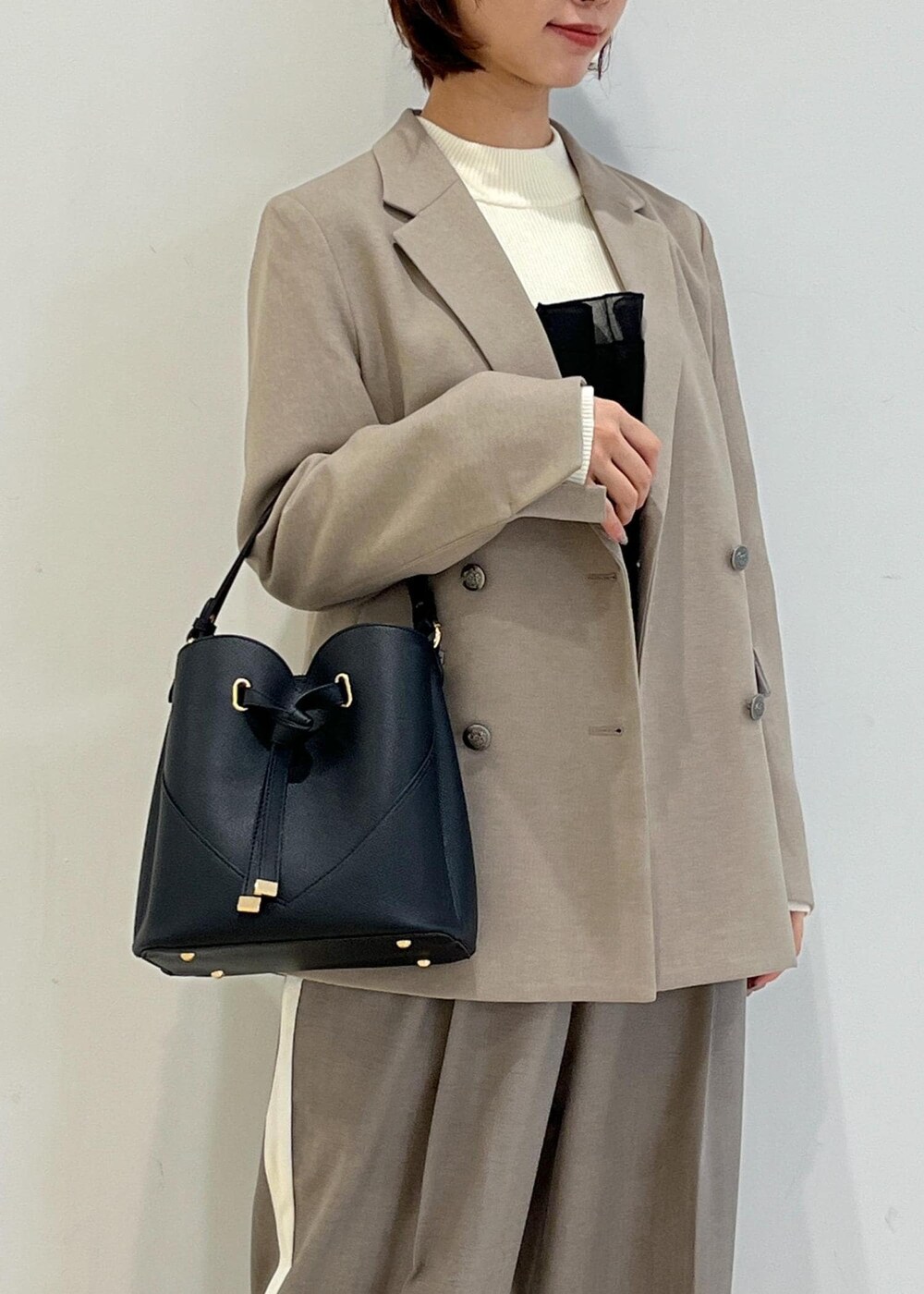 ブラック系のパンプス、ホワイト系のニット/セーター、ベージュ系のテーラードジャケットを着用したレディースの冬コーディネートの9枚目の写真