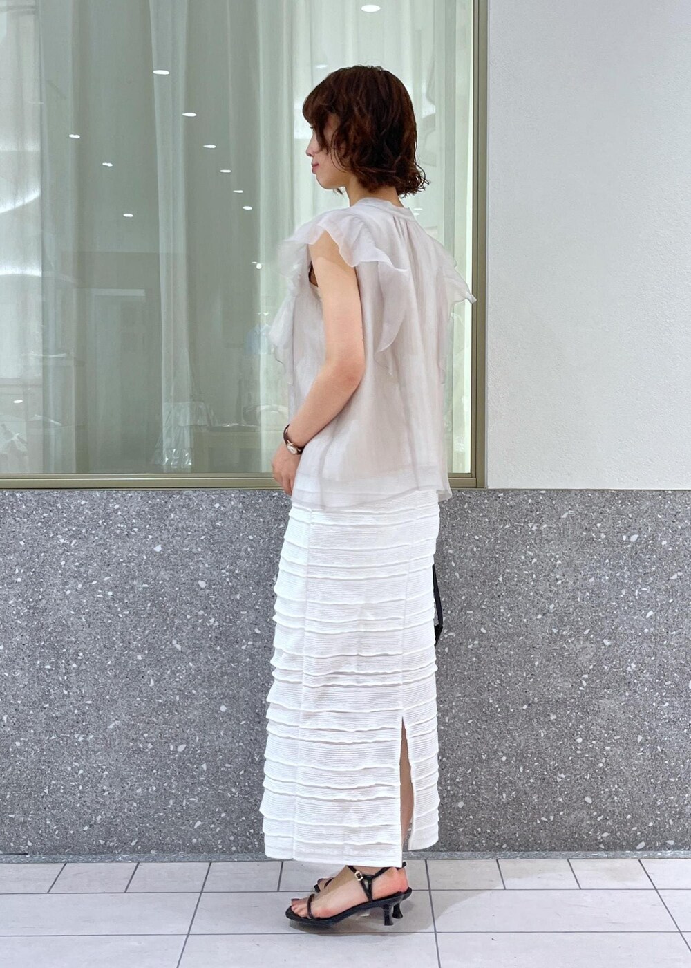 ブラック系のサンダル、ホワイト系のスカート、ホワイト系のキャミソールを着用したレディースの春コーディネートの3枚目の写真