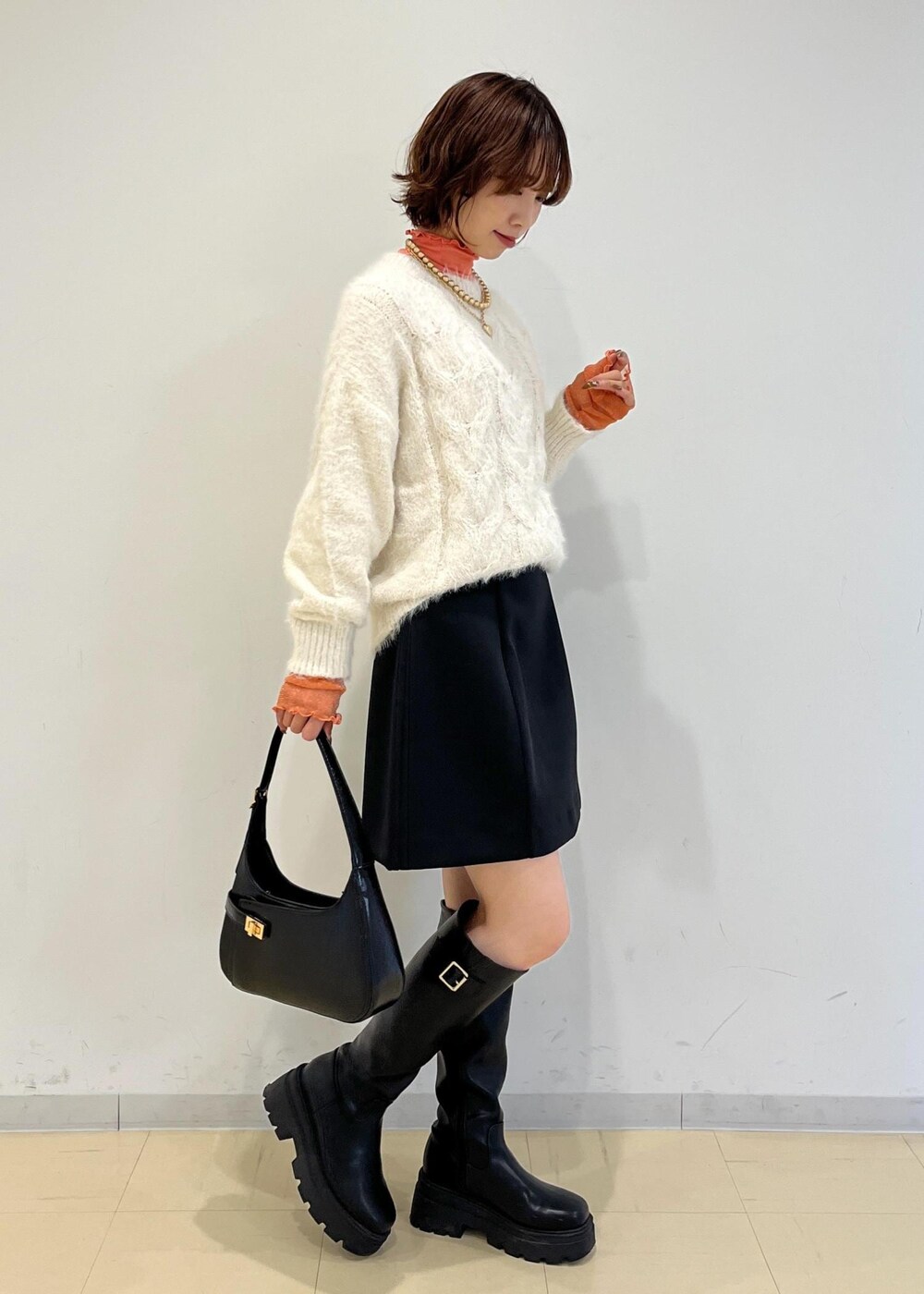 ブラック系のブーツ、ブラック系のハンドバッグ、ブラック系のスカートを着用したレディースの冬コーディネートの4枚目の写真