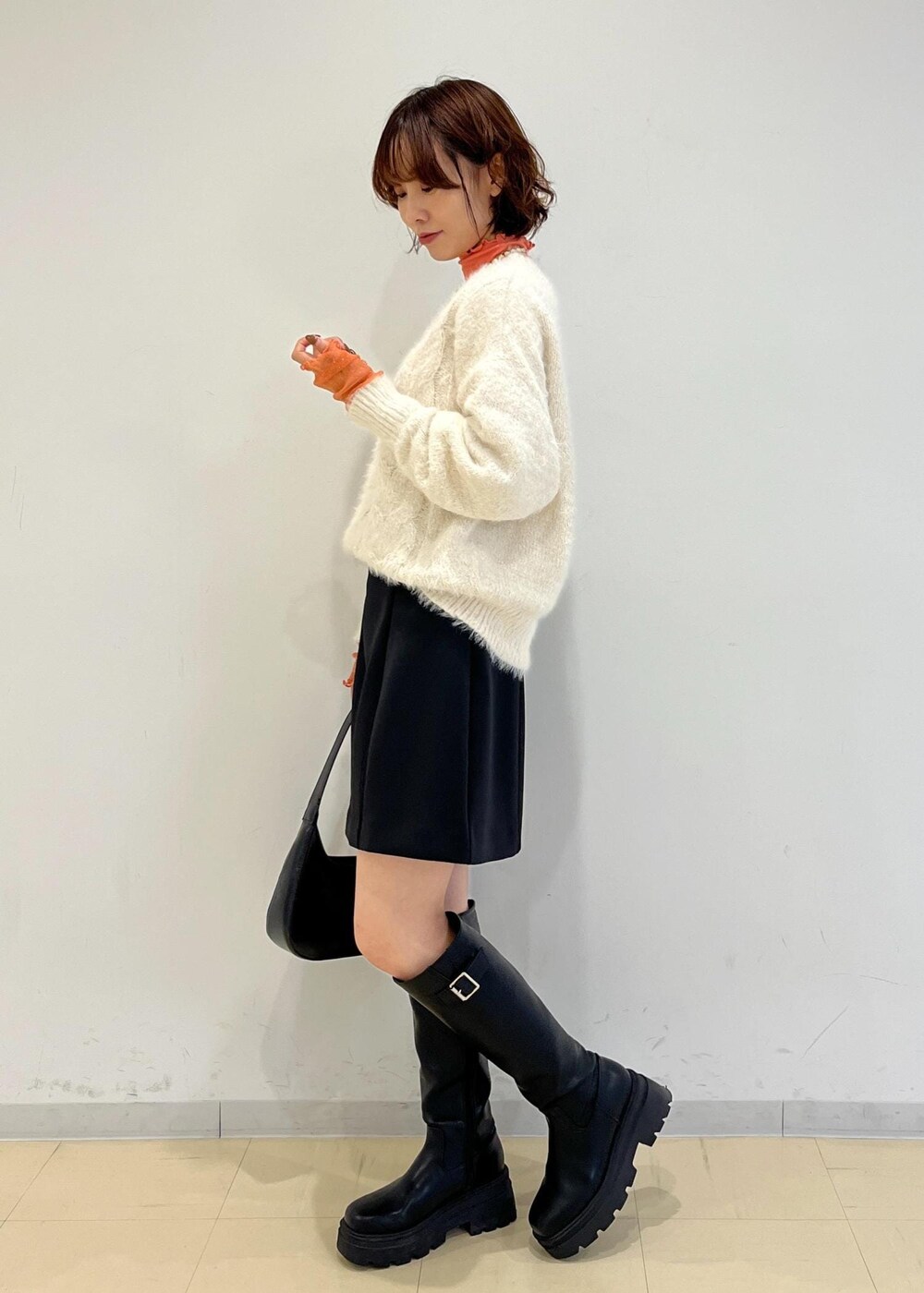 ブラック系のブーツ、ブラック系のハンドバッグ、ブラック系のスカートを着用したレディースの冬コーディネートの2枚目の写真