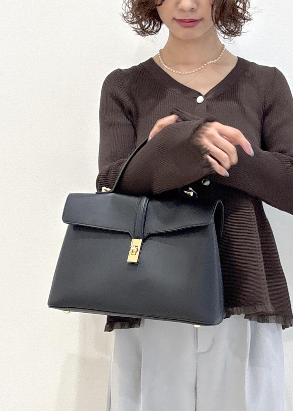 ブラック系のハンドバッグ、ブルー系のその他パンツ、ブラック系のパンプスを着用したレディースの秋コーディネートの9枚目の写真