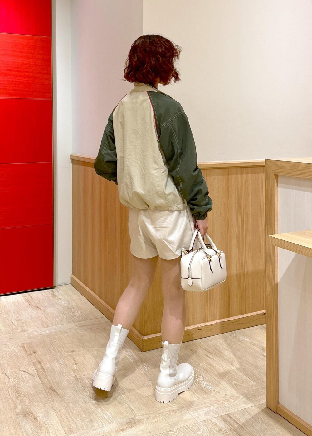 ホワイト系のブーツ、ホワイト系のボストンバッグ、ベージュ系のスラックスを着用したレディースの冬コーディネートの4枚目の写真