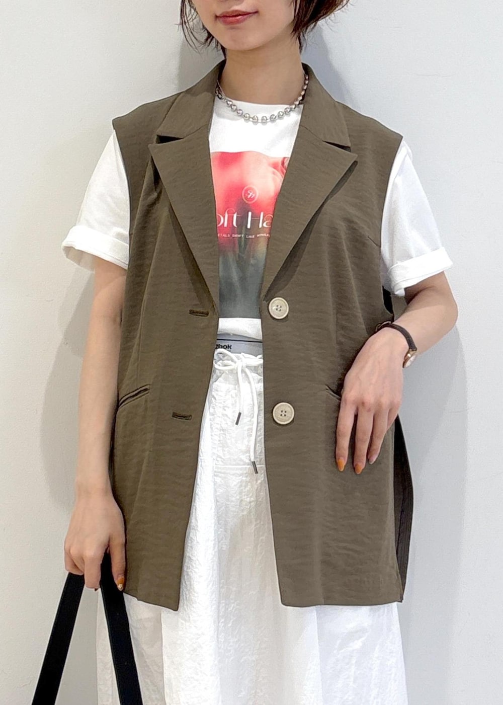 ブラック系のショルダーバッグ、ブラック系のバレエシューズ、ホワイト系のTシャツ/カットソーを着用したレディースの春コーディネートの5枚目の写真