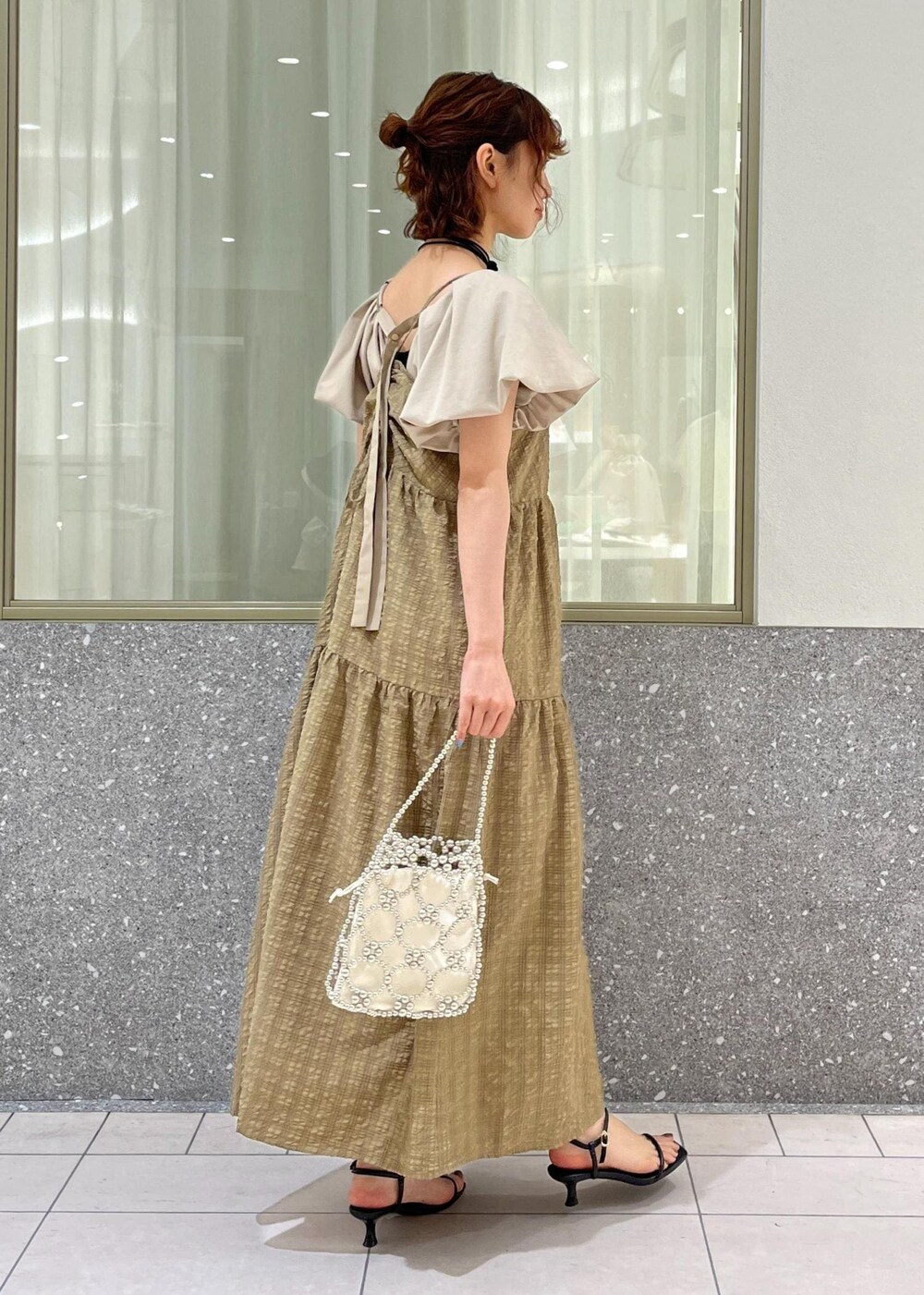 ブラック系のサンダル、ベージュ系のTシャツ/カットソー、ブラウン系のワンピースを着用したレディースの春コーディネートの3枚目の写真