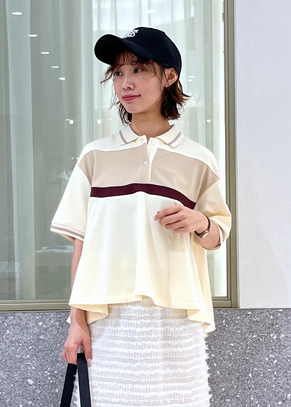 ブラック系のサンダル、ホワイト系のスカート、ベージュ系のポロシャツを着用したレディースの夏コーディネートの7枚目の写真