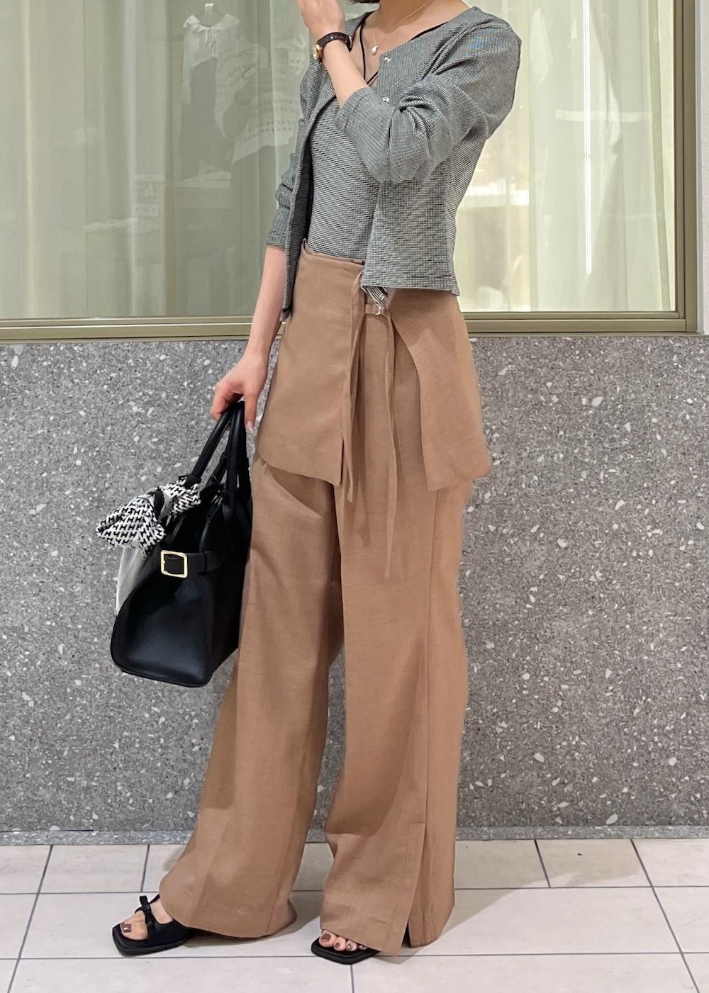 ブラック系のサンダル、ブラウン系のスラックス、ブラック系のトートバッグを着用したレディースの夏コーディネートの3枚目の写真