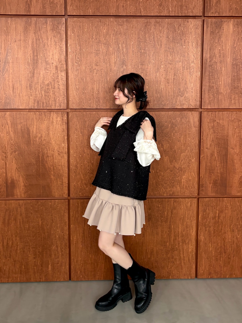 ブラック系のベスト、ベージュ系のスカートを着用したレディースの春コーディネートの2枚目の写真