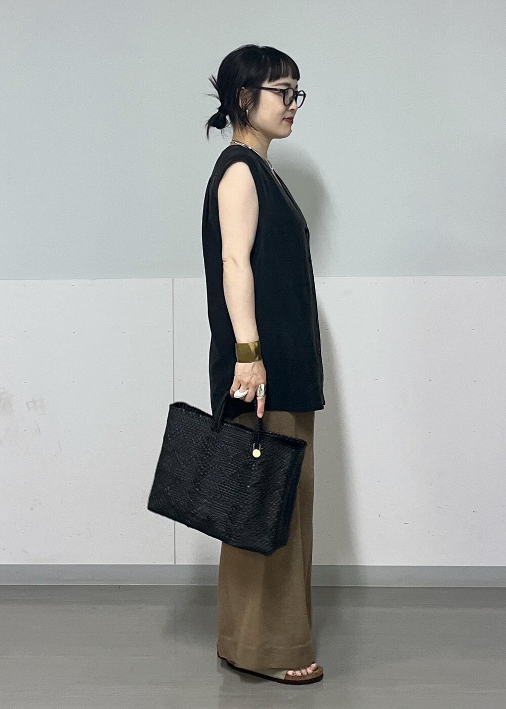 ブラック系のチューブトップ、ブラック系のベスト、ブラック系のかごバッグを着用したレディースの夏コーディネートの2枚目の写真