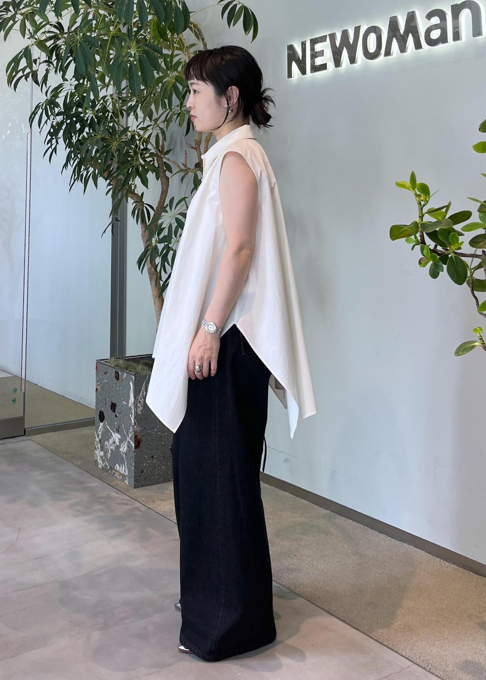 グレー系のデニムパンツ、ホワイト系のシャツ/ブラウス、ブラウン系のショルダーバッグを着用したレディースの夏コーディネートの2枚目の写真