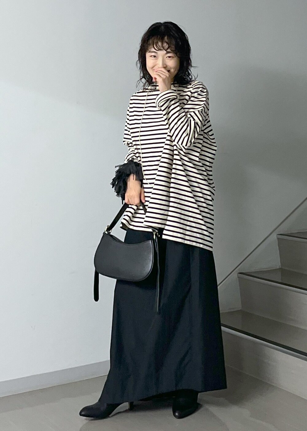 ブラック系のスカート、レッド系のカーディガン/ボレロ、ブラック系のショルダーバッグを着用したレディースの秋コーディネートの2枚目の写真