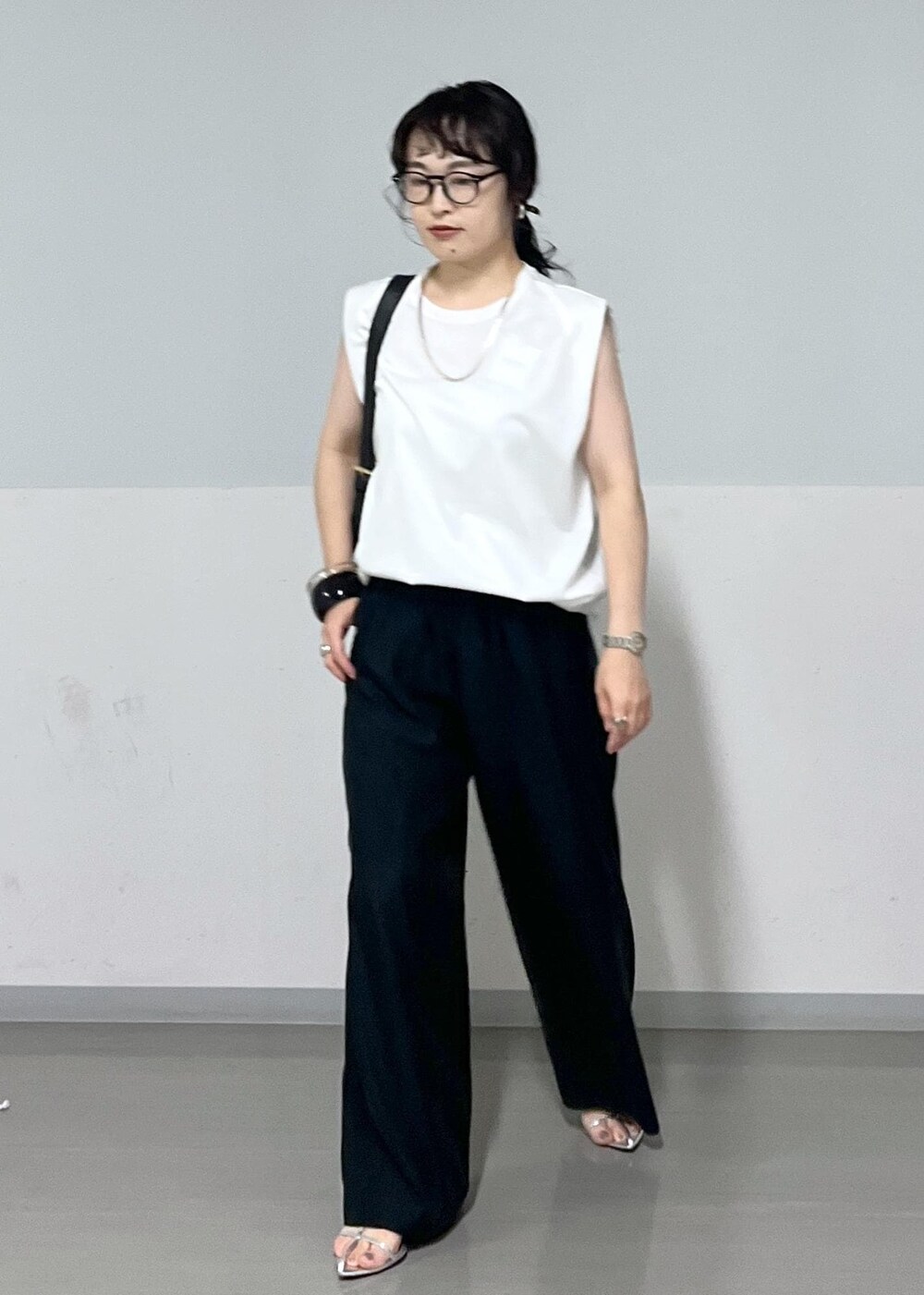 シルバー系のサンダル、ホワイト系のTシャツ/カットソー、ブラック系のその他パンツを着用したレディースの夏コーディネートの2枚目の写真