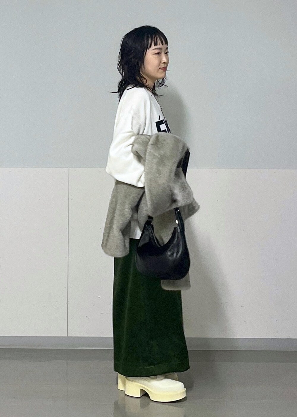グリーン系のスカート、ホワイト系のシャツ/ブラウス、グレー系のブルゾンを着用したレディースの冬コーディネートの2枚目の写真