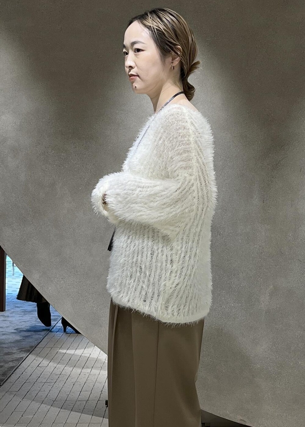 ベージュ系のスラックス、ベージュ系のチェスターコート、ホワイト系のニット/セーターを着用したレディースの秋コーディネートの8枚目の写真