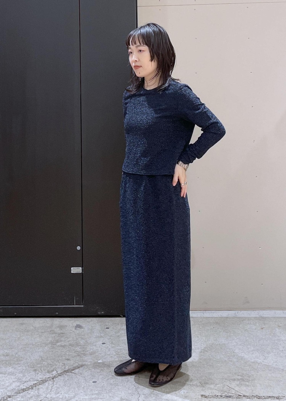 ブラック系のトートバッグ、ブラック系のパンプス、ブルー系のスカートを着用したレディースの冬コーディネートの4枚目の写真