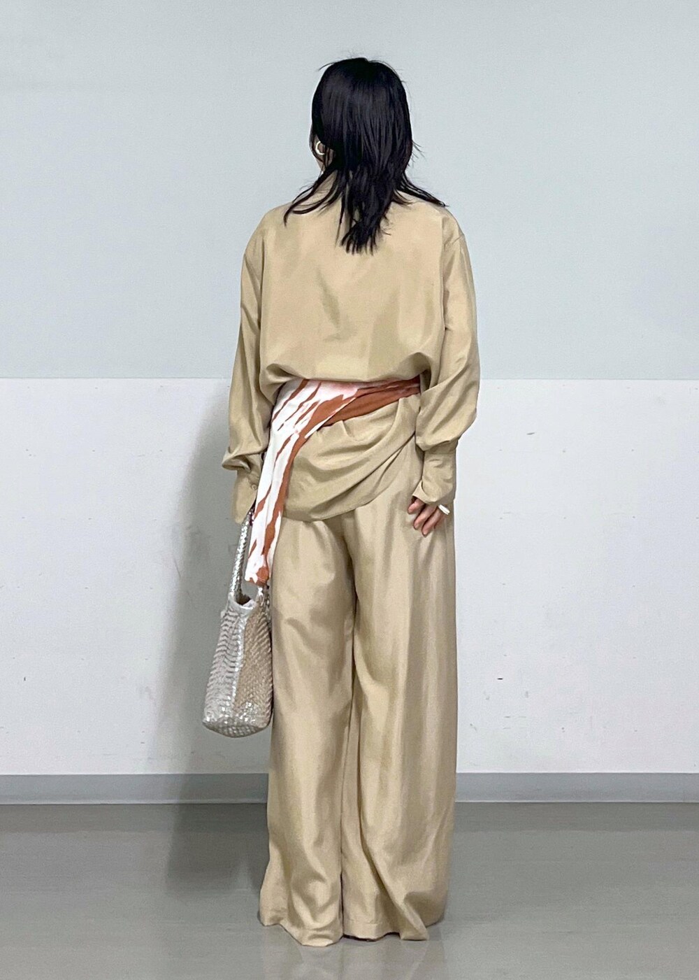 シルバー系のトートバッグ、ベージュ系のシャツ/ブラウス、ブラウン系のTシャツ/カットソーを着用したレディースの春コーディネートの2枚目の写真