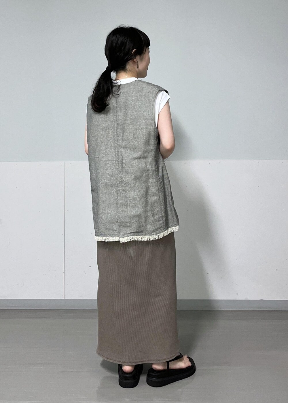 ブラック系のベスト、ホワイト系のTシャツ/カットソー、ブラック系のサンダルを着用したレディースの夏コーディネートの4枚目の写真