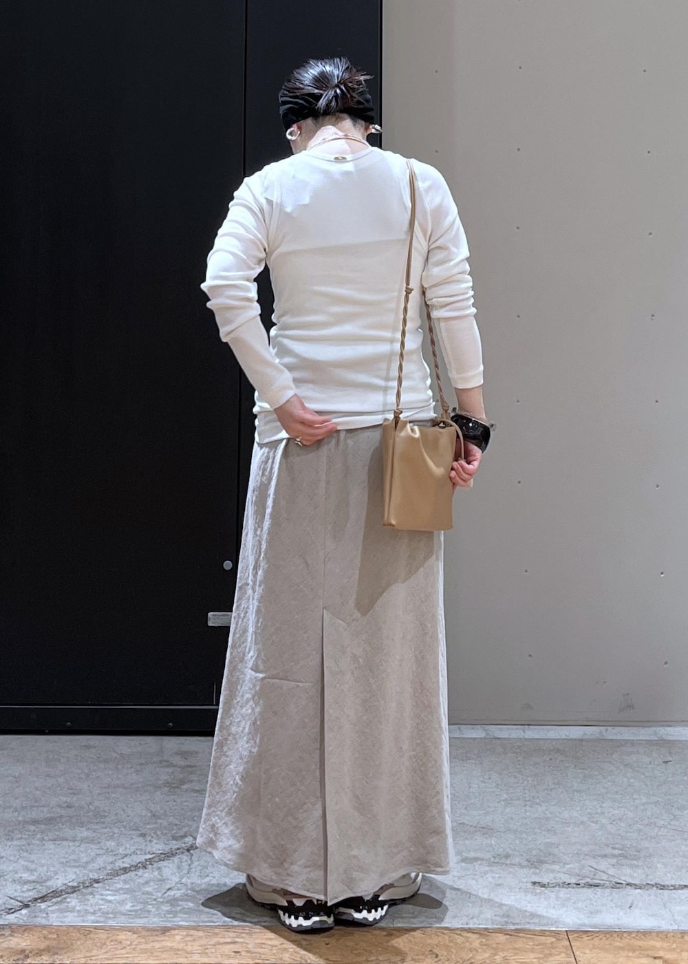 ベージュ系のスニーカー、ベージュ系のスカート、ホワイト系のタンクトップを着用したレディースの春コーディネートの3枚目の写真