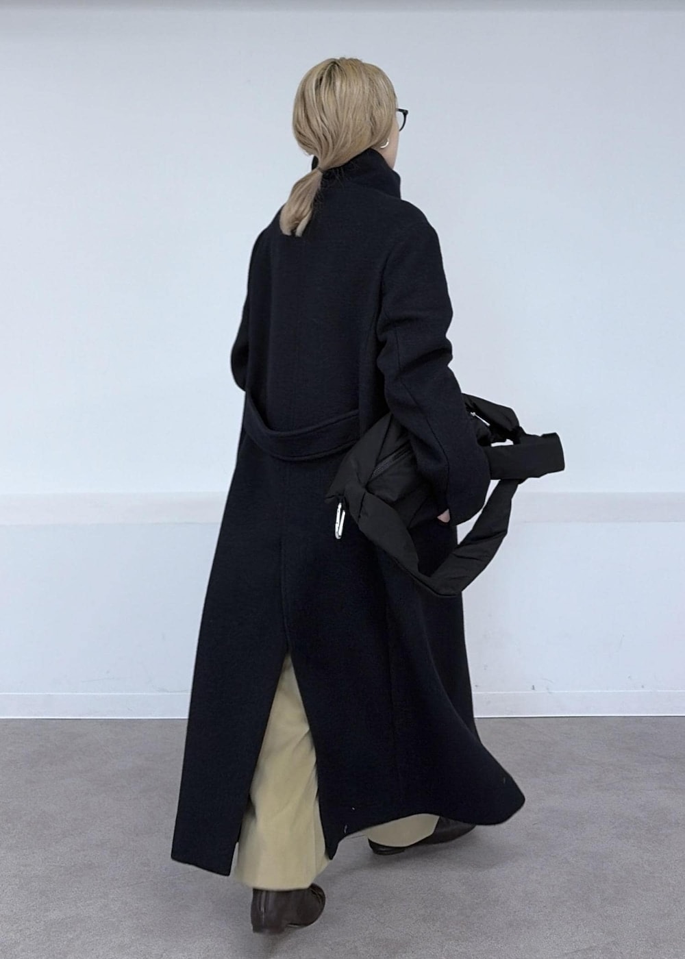 ベージュ系のその他パンツ、グレー系のダウンジャケット/コート、ブラック系のショルダーバッグを着用したレディースの秋コーディネートの4枚目の写真