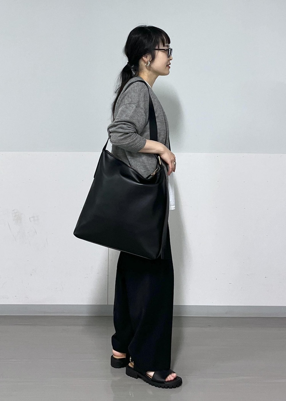 ブラック系のサンダル、グレー系のカーディガン/ボレロ、ブラック系のスラックスを着用したレディースの春コーディネートの3枚目の写真