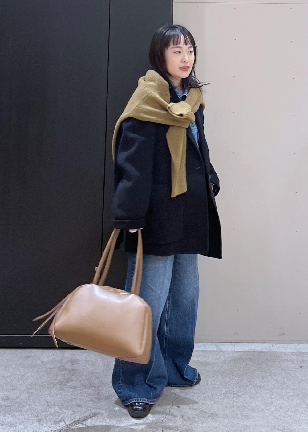 イエロー系のニット/セーター、ブルー系のデニムパンツ、ブラック系のその他アウターを着用したレディースの冬コーディネートの2枚目の写真