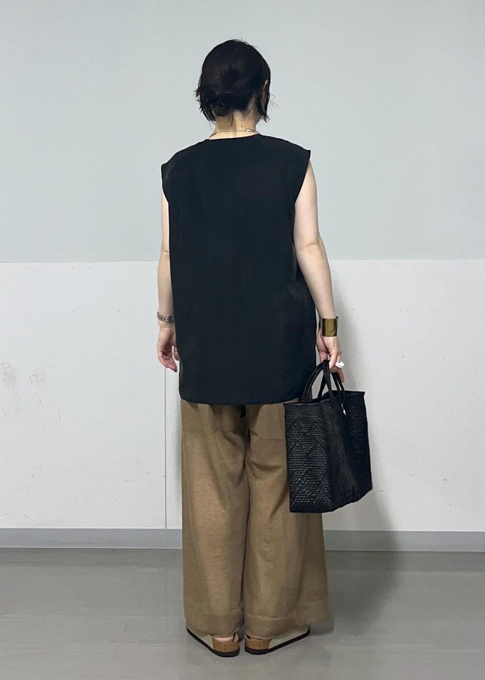 ブラック系のチューブトップ、ブラック系のベスト、ブラック系のかごバッグを着用したレディースの夏コーディネートの3枚目の写真