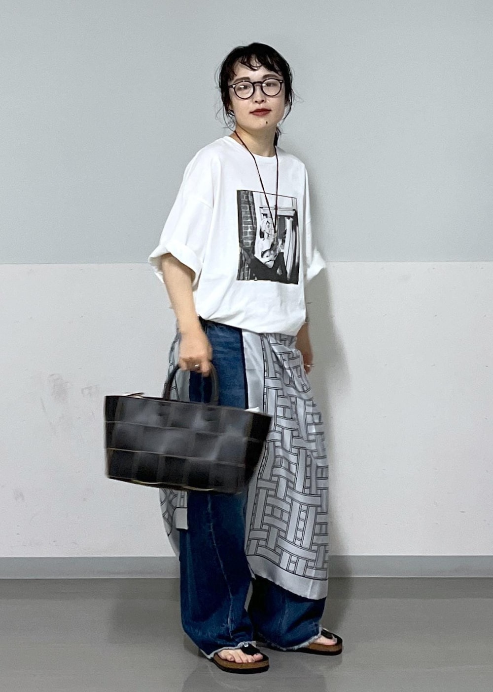 ブラック系のトートバッグ、ブルー系のデニムパンツ、ホワイト系のTシャツ/カットソーを着用したレディースの夏コーディネートの2枚目の写真