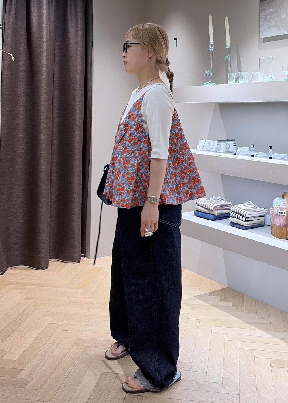 ブラック系のハンドバッグ、ベージュ系のサンダル、ブルー系のデニムパンツを着用したレディースの夏コーディネートの2枚目の写真