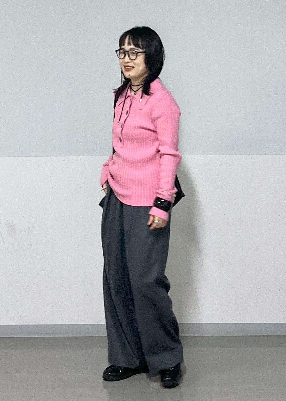 グレー系のスラックス、ブラック系のトートバッグ、ピンク系のニット/セーターを着用したレディースの冬コーディネートの2枚目の写真