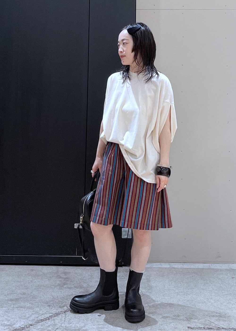 ブラック系のボストンバッグ、ブラック系のブーツ、ホワイト系のTシャツ/カットソーを着用したレディースの冬コーディネートの2枚目の写真