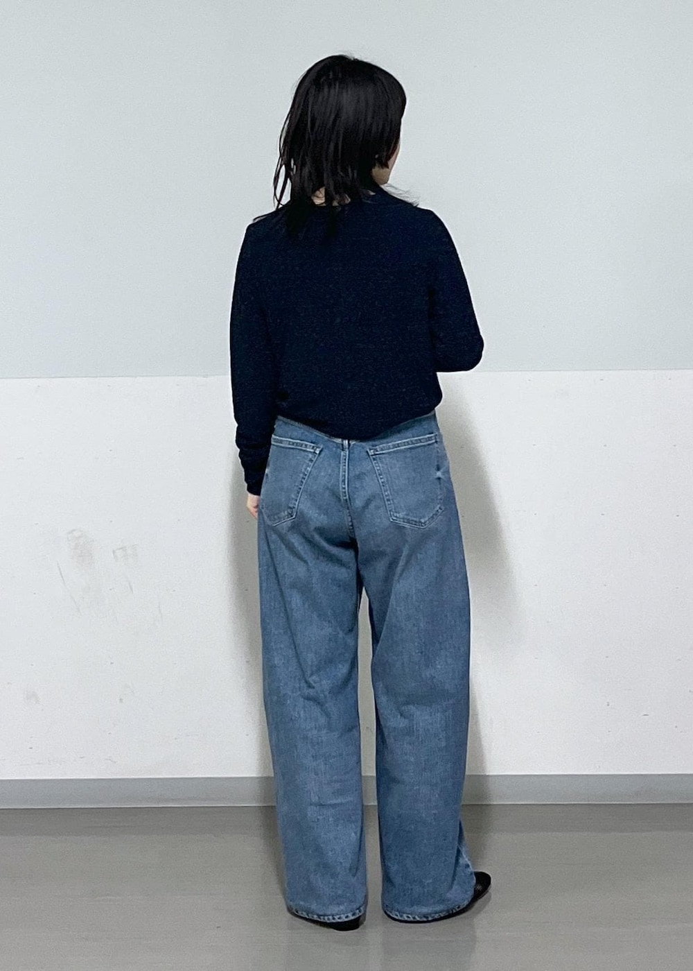 ブラック系のパンプス、ブルー系のデニムパンツ、ホワイト系のカーディガン/ボレロを着用したレディースの冬コーディネートの6枚目の写真