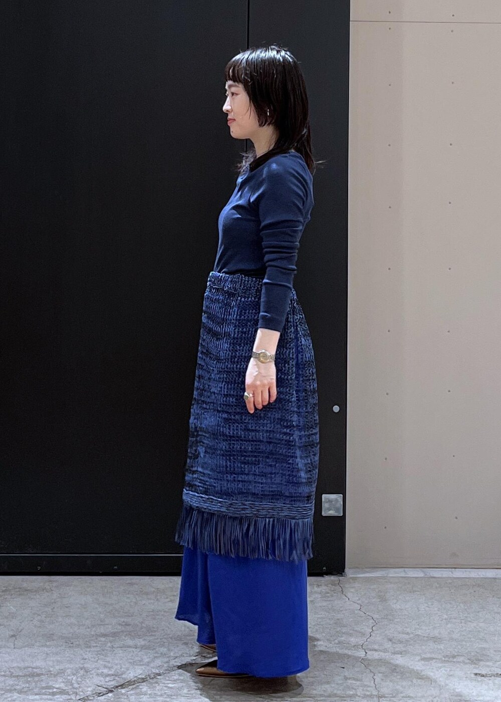 ブラック系のショルダーバッグ、その他のパンプス、ブルー系のスカートを着用したレディースの春コーディネートの2枚目の写真