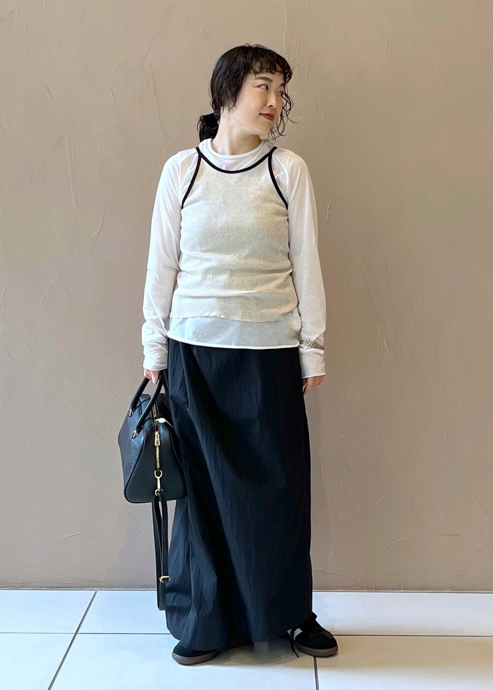 ブラック系のスカート、ベージュ系のタンクトップ、ホワイト系のTシャツ/カットソーを着用したレディースの夏コーディネートの2枚目の写真