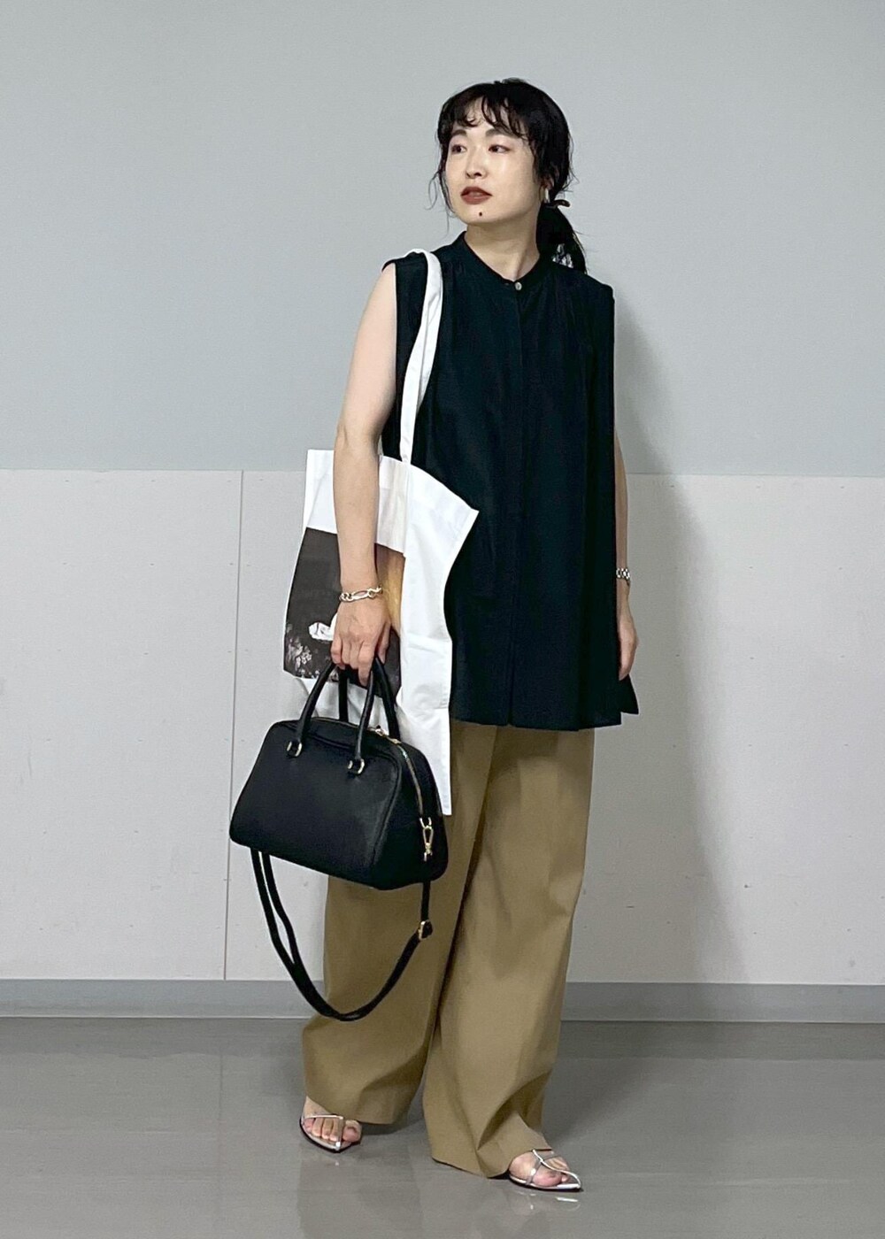 ベージュ系のその他パンツ、シルバー系のサンダル、ホワイト系のトートバッグを着用したレディースの夏コーディネートの2枚目の写真