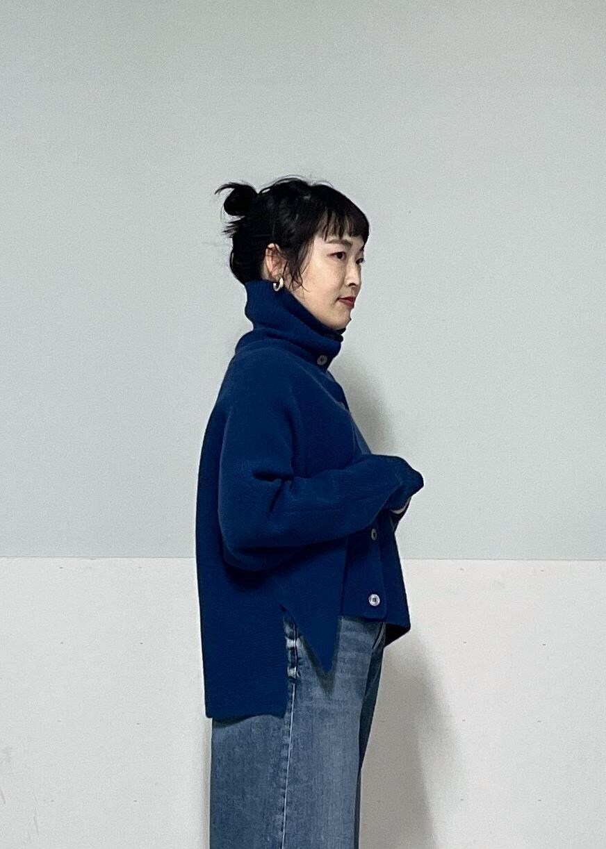 ホワイト系のボストンバッグ、ブルー系のニット/セーター、ブラック系のブーツを着用したレディースの秋コーディネートの6枚目の写真