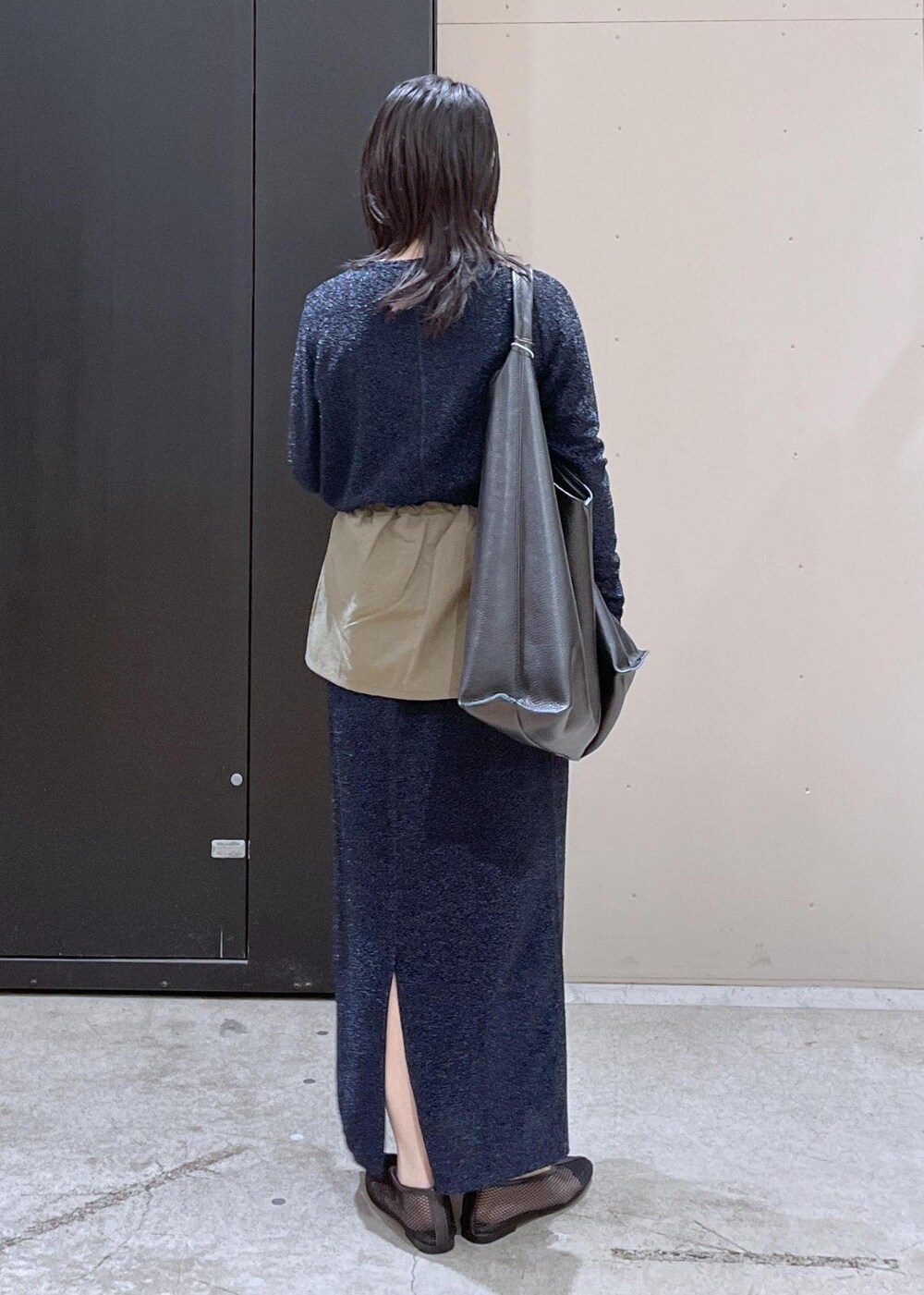 ブラック系のトートバッグ、ブラック系のパンプス、ブルー系のスカートを着用したレディースの冬コーディネートの3枚目の写真