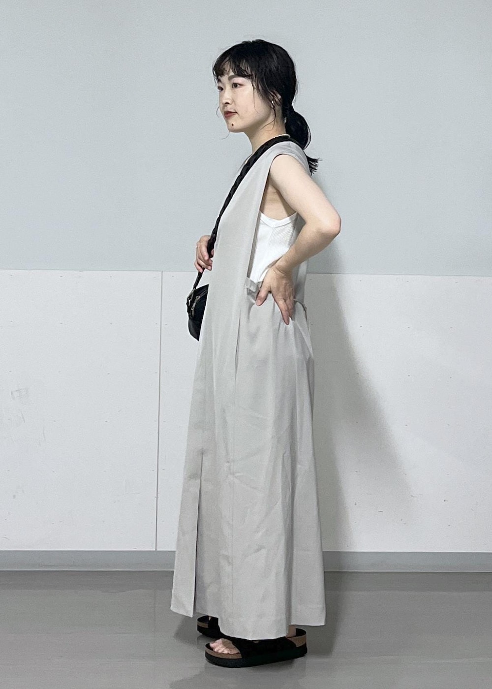 ブラック系のサンダル、ベージュ系のジャンパースカート、ホワイト系のタンクトップを着用したレディースの夏コーディネートの2枚目の写真