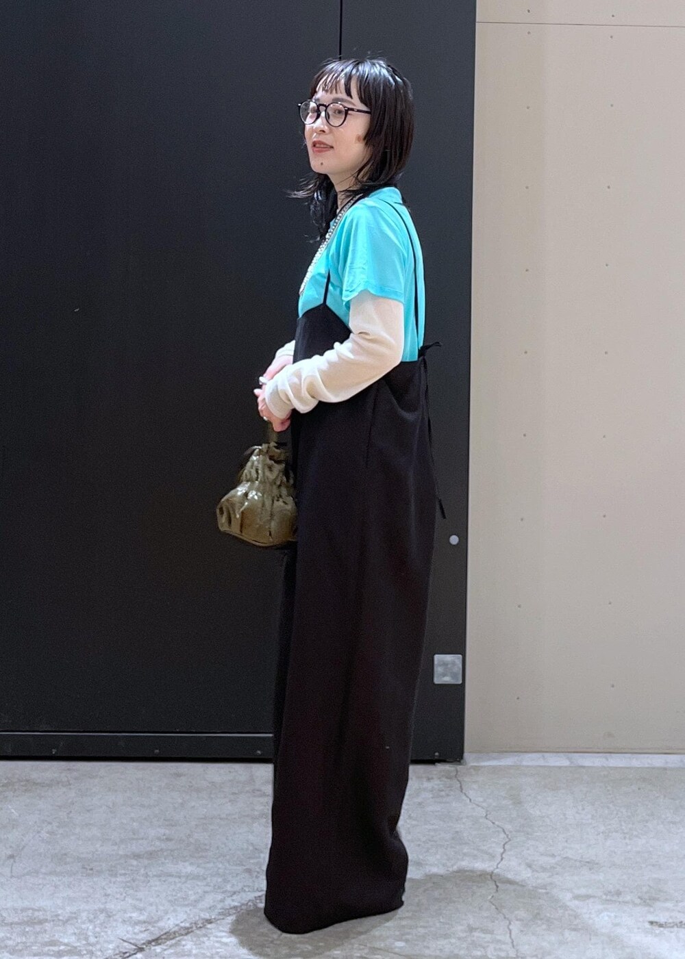 グリーン系のショルダーバッグ、ブラック系のサロペット/オーバーオール、ブルー系のTシャツ/カットソーを着用したレディースの冬コーディネートの2枚目の写真